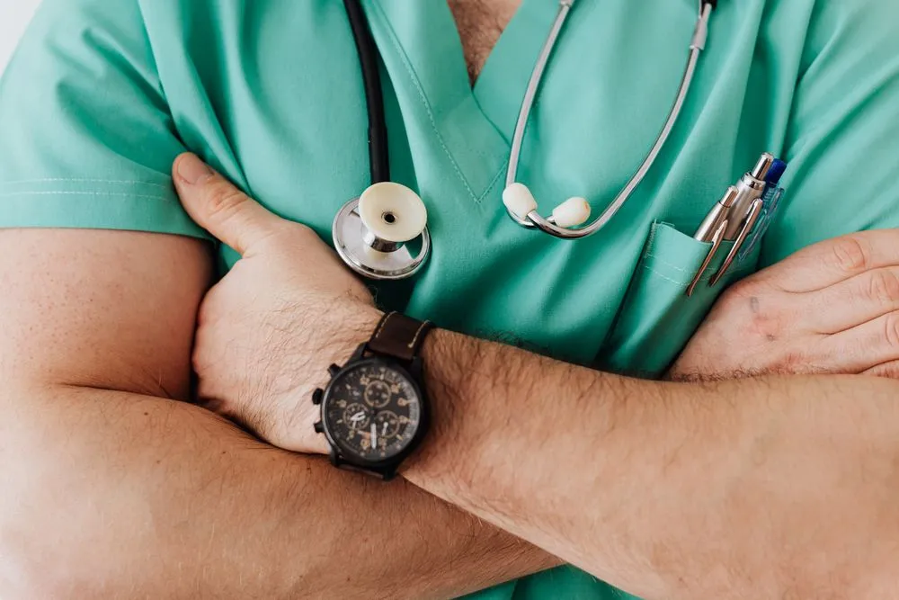 Profesional de salud con scrubs y estetoscopio cruzado de brazos