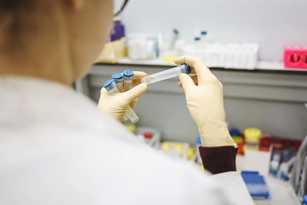 Manos con guantes manipulando una muestra en el laboratorio